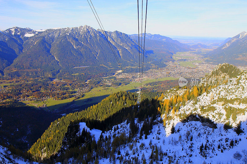 以上Garmisch Partenkirchen阿尔卑斯村在巴伐利亚阿尔卑斯山从Alpspitze，田园诗般的松树林地秋季景观，雄伟的阿尔卑斯山谷，戏剧性的巴伐利亚德国雪山全景，德国